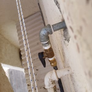 צינור מתכת עם ברז פלסטיק על קיר