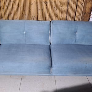 ספה כחולה עם כתמים קלים על רצפת מרפסת