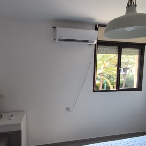 חדר עם מזגן מותקן על הקיר ומנורה תלויה
