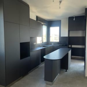 מטבח נקי עם משטחי עבודה כהים וכיור