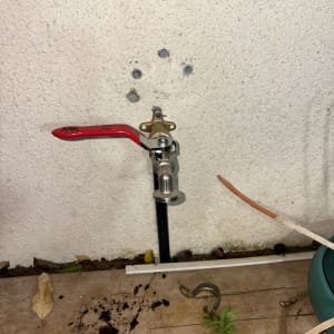 ברז מים מותקן על קיר חיצוני עם ידית אדומה