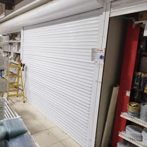 תריס גלילה לבן סגור בחנות עם מדפים