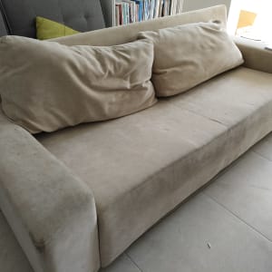 ספה בהירה עם כריות על רצפת אריחים