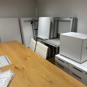 חדר עם שולחן עץ וכיסאות, לוחות לבנים מוערמים