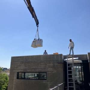 מנוף מרים חבילות לגג בניין עם אנשים על הגג