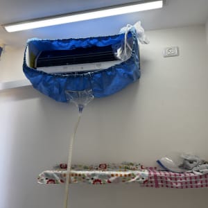 מזגן עם כיסוי כחול וצינור ניקוז על קיר