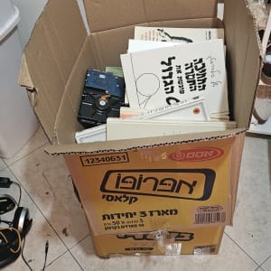קופסת קרטון עם ספרים ודיסק קשיח על רצפה
