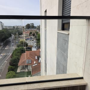 מעקה זכוכית במרפסת עם נוף עירוני