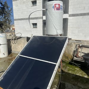 מערכת חימום סולארית על גג בניין עם דוד שמש וקולטים.