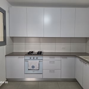 מטבח מודרני עם ארונות לבנים וכיריים גז