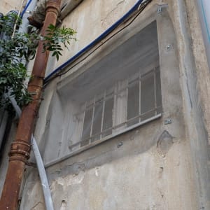 קיר עם צינורות, כבלים וסורגים על חלון