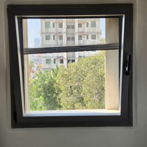 חלון פתוח עם נוף של בניין ועצים בחוץ