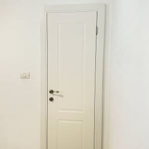 דלת לבנה עם ידית מתכת על קיר לבן