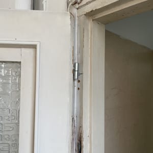 דלת עץ לבנה עם צירים וחיבורים חשופים