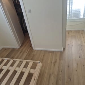 התקנת פרקט בגוון עץ טבעי עם פנלים לבנים בחדר שינה