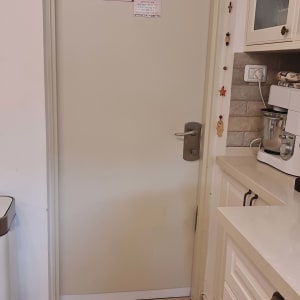 דלת לבנה עם ידית מתכת ושלטים צבעוניים