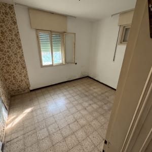 חדר ריק עם רצפת אריחים וקיר עם טפט פרחוני