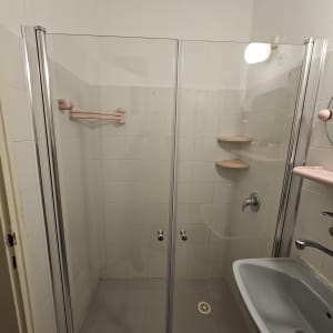 מקלחון עם דלתות זכוכית, מדפים וברזים