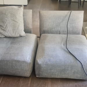 ספות אפורות עם כריות וחוט חשמל על הרצפה