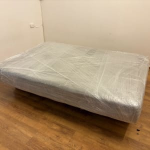 מיטה עטופה בניילון על רצפת עץ