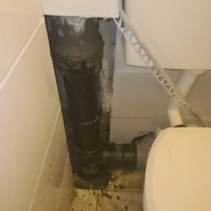 צינור ביוב שחור עם חיבורים ליד אסלה