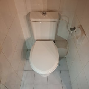 אסלה לבנה בחדר אמבטיה עם אריחים לבנים