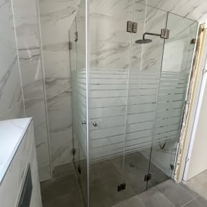 מקלחון זכוכית עם דלתות שקופות ופסים חלביים