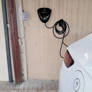 עמדת טעינה לרכב חשמלי על קיר עם כבל טעינה