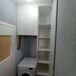 ארון לבן עם מדפים פתוחים ליד מכונת כביסה
