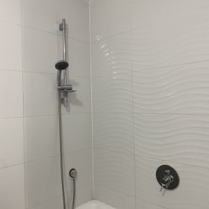 מקלחת עם אריחים לבנים וברז מתכת