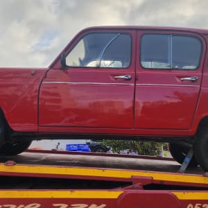 מכונית אדומה על גרר עם רצועות קשירה