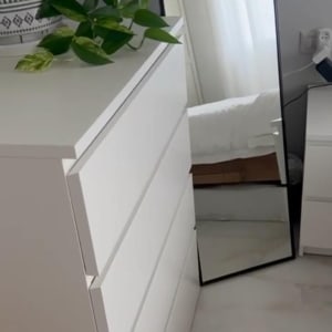 מראה עומדת ליד שידה לבנה בחדר שינה