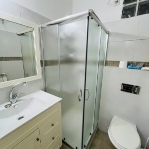 מקלחון זכוכית בחדר אמבטיה עם כיור ושירותים