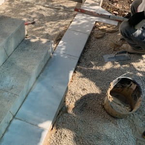 עבודת ריצוף חוץ באבן בעזרת פלס וכלי עבודה