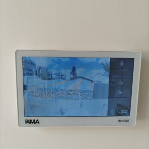 מסך אינטרקום מותקן על קיר לבן