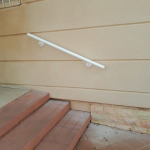 מעקה לבן מותקן על קיר מעל מדרגות