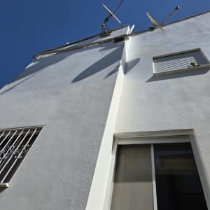 חזית בניין גבוהה צבועה בלבן מול שמיים כחולים