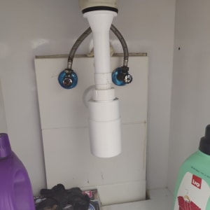 צינור ניקוז לבן מתחת לכיור עם ברזים