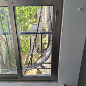 חלון זכוכית עם נוף חיצוני של צמחייה ומזגן