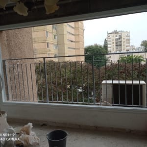 חלון גדול עם מסגרת לבנה וסורגי מתכת