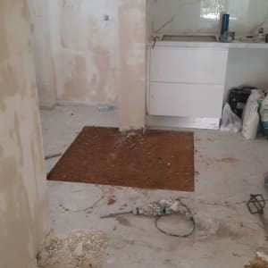 קיר עם טיח מתקלף, רצפה עם חפירה, כלי עבודה