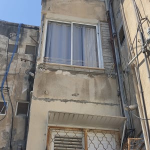 חזית בניין מגורים עם צינורות אינסטלציה חיצוניים ותיקוני טיח ואיטום בגובה