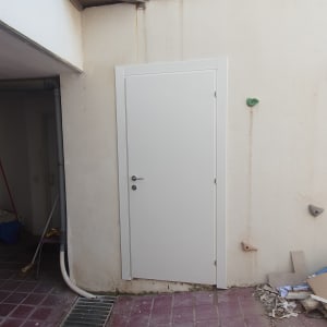 דלת לבנה עם ידית כסופה על קיר חיצוני