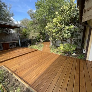 דק עץ בגינה עם עצים וצמחייה מסביב