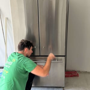 אדם עובד על מקרר נירוסטה בחלל עבודה