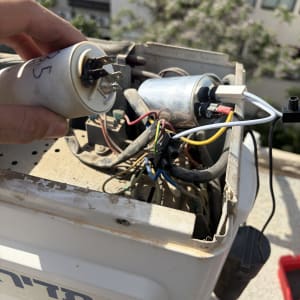 תיקון מזגן עם חלקים חשמליים וחוטים חשופים