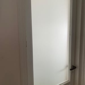 דלת זכוכית חלבית עם מסגרת לבנה וידית שחורה