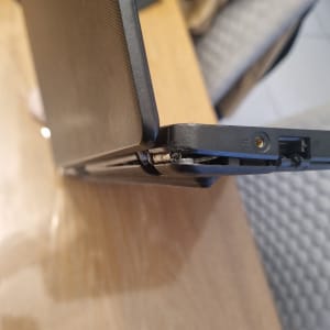 מחשב נייד עם ציר שבור על שולחן עץ