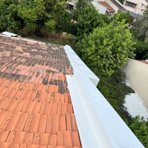 רעפים כתומים על גג עם תעלה לבנה בצד