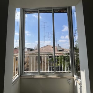 חלון גדול עם נוף לגגות ולשמיים כחולים